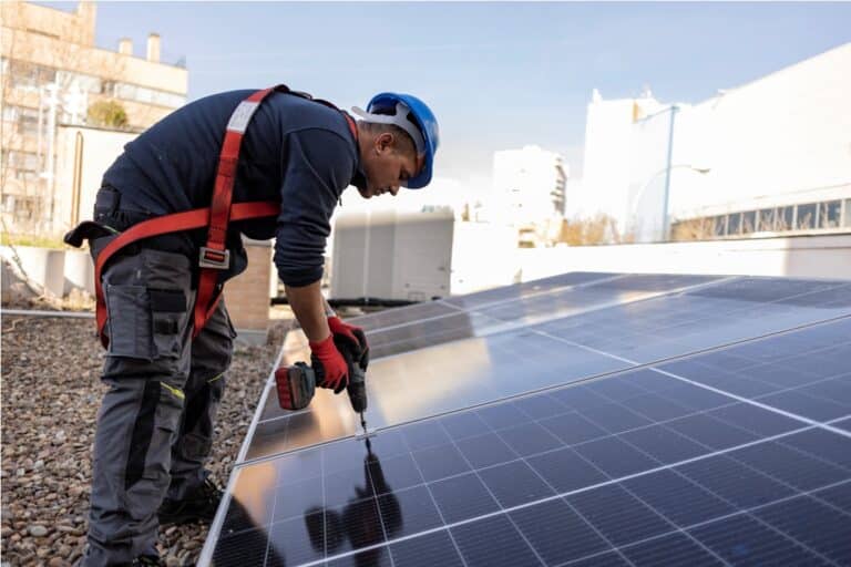 solar panel worker screwing solar panel on the roof