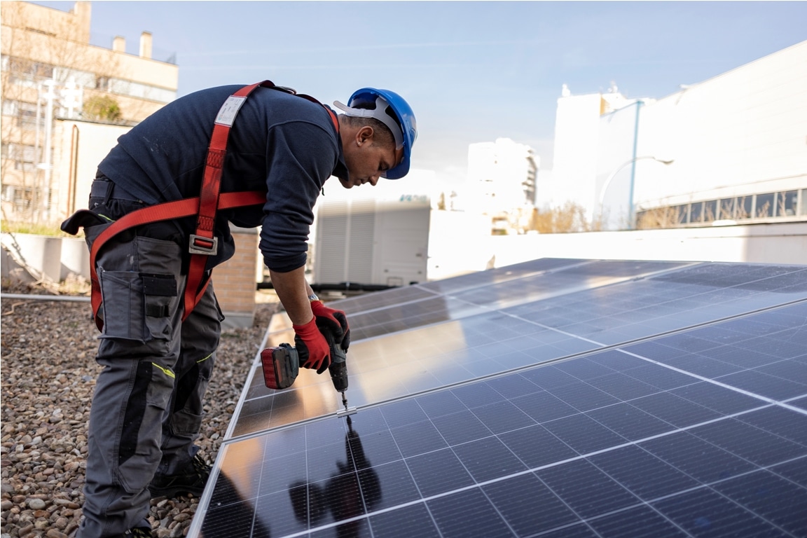 solar panel worker screwing solar panel on the roof